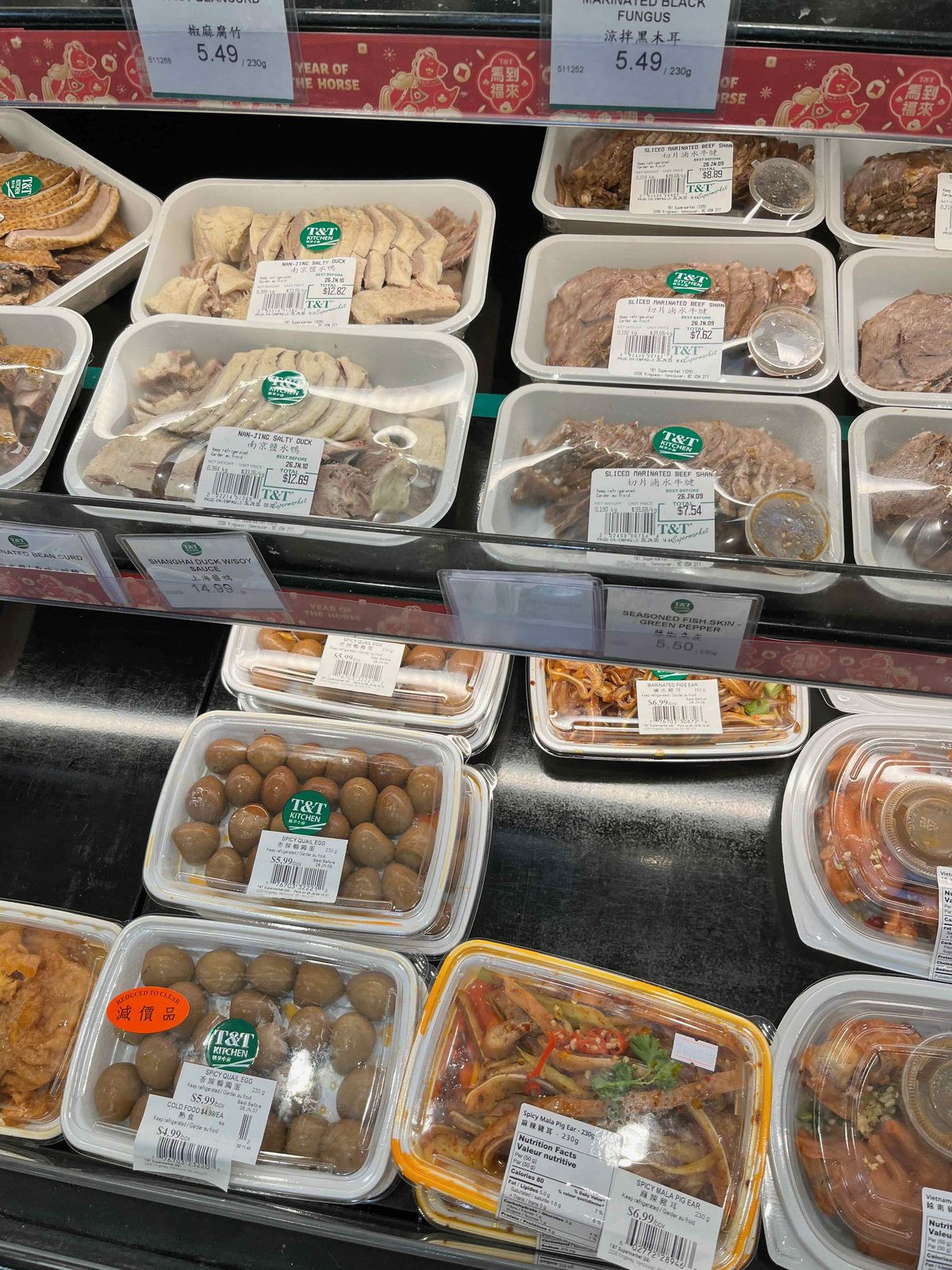 T&Tの惣菜ショーケース。塩水鴨や牛すね肉、うずら卵の煮物が値札付きで並び、うずら卵には減價品の値下げシールが貼られている
