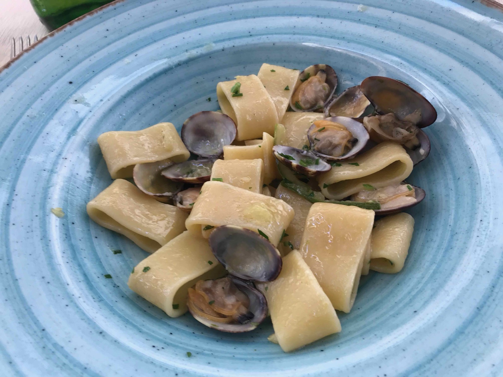 水色の陶器皿に盛られたあさりのパスタ（パッケリ）