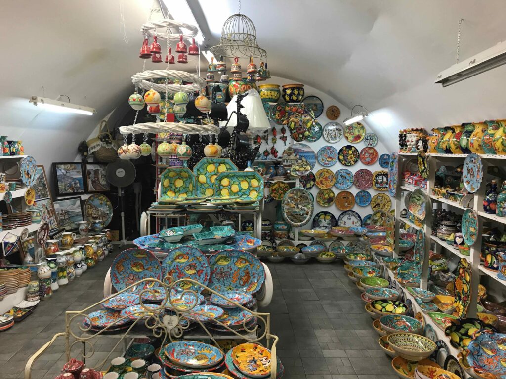 ビエトリの陶器店の店内。天井から吊るされたオーナメント、壁一面の絵皿、床に並ぶ大皿